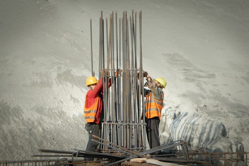 Two construction workers assembling steel reinforcement at a building site