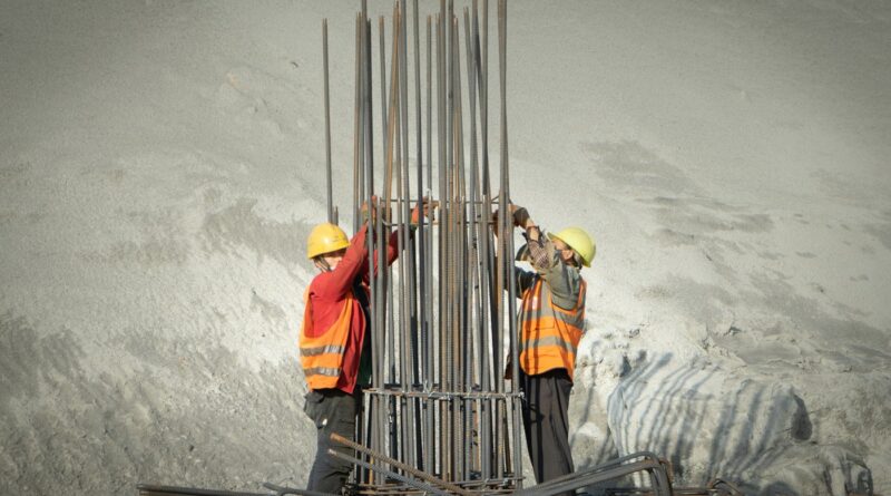 Two construction workers assembling steel reinforcement at a building site